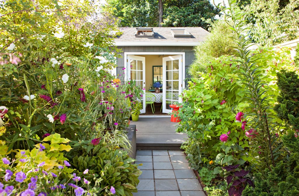 Garden beds with flowers leading to a small garden shed