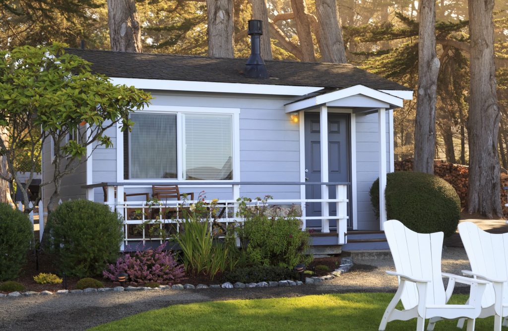 Tiny house with blue gray siding and lawn chairs