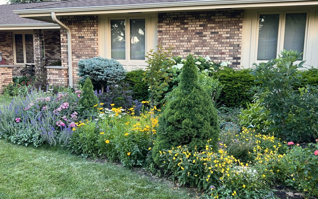 Pollinator garden in front lawn with flowers, bushes, and trees