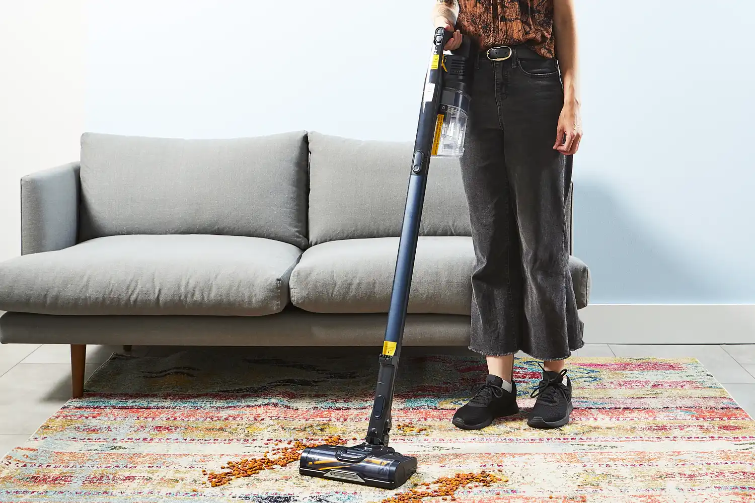 Person using Shark Pet Pro Cordless Stick Vacuum Cleaner to clean pet kibble on the carpet