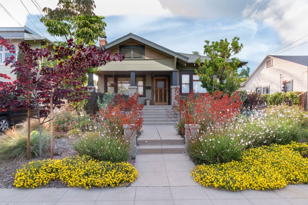 Front of home with red and yellow plants and flowers